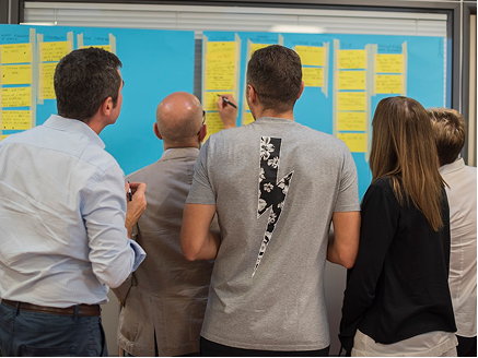 Team arbeitet gemeinsam an einem Workshop-Board als Symbol für Projektbegleitung, Coaching und Servant Leadership mit MPoweredHub in CRM- und No-/Low-Code-Projekten.